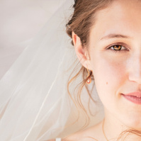 This portrait captures a poetic stillness—half of a young bride's face softly lit, framed by delicate wisps of hair and the gentle fall of her veil. There's a quiet strength and vulnerability in her expression, evoking the romantic resilience of Les Mis