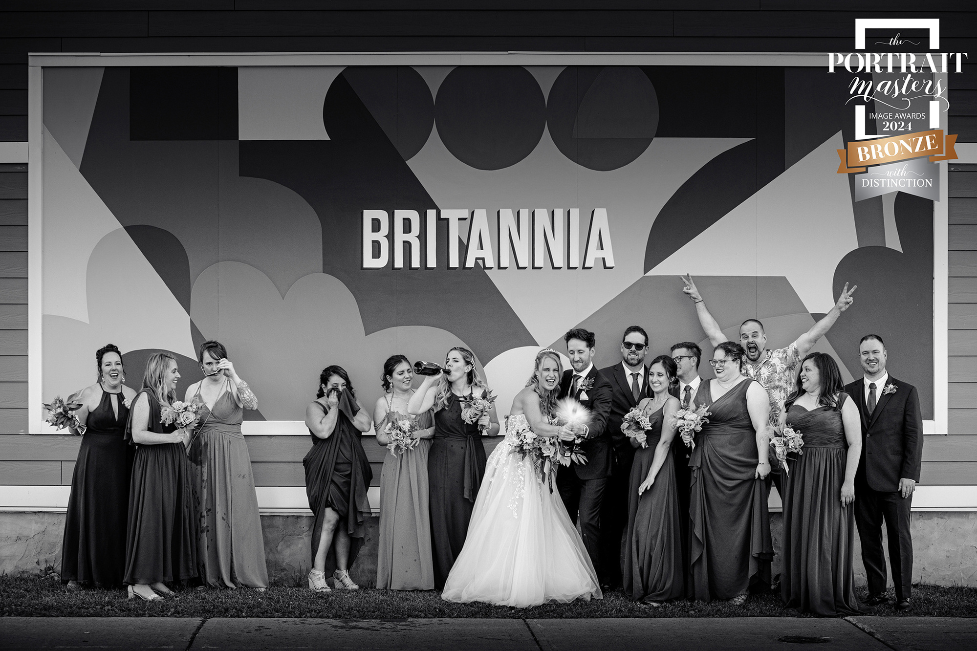 Award winning photograph of couple and bridal party in front of Brittania sign by Frank Fenn