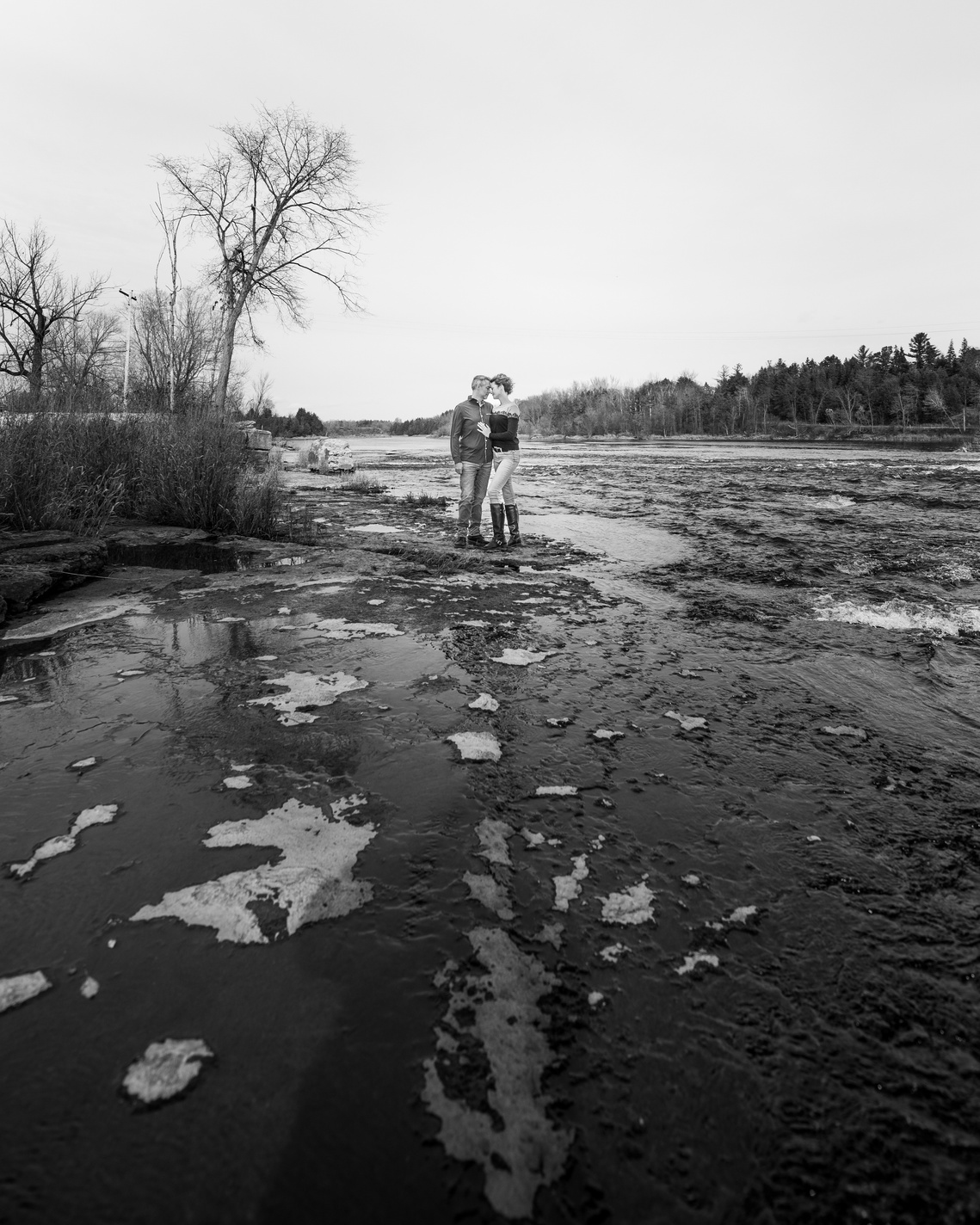 Black and white photograph of couple standing on rocks in the rapids in Pakenham by Frank Fenn Ottawa Photographer