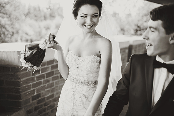 The bride is walking with her groom, holding a bridal bouquet. The person is wearing a J'Aton Couture dress. The other person is wearing a black suit.