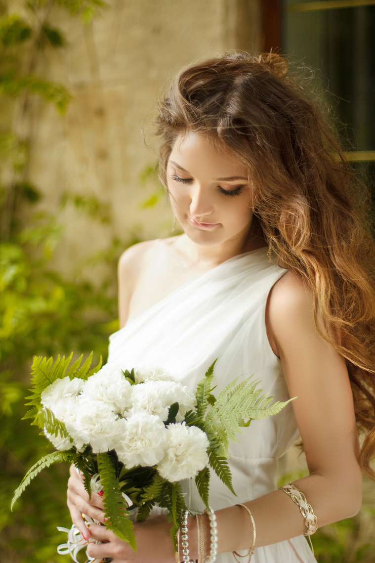 Bride is looking at her bridal bouquet at Captain James cottage in Melbourne. The flowers are from Hailey Page Flowers. The brides dress is Tania Olsen.  