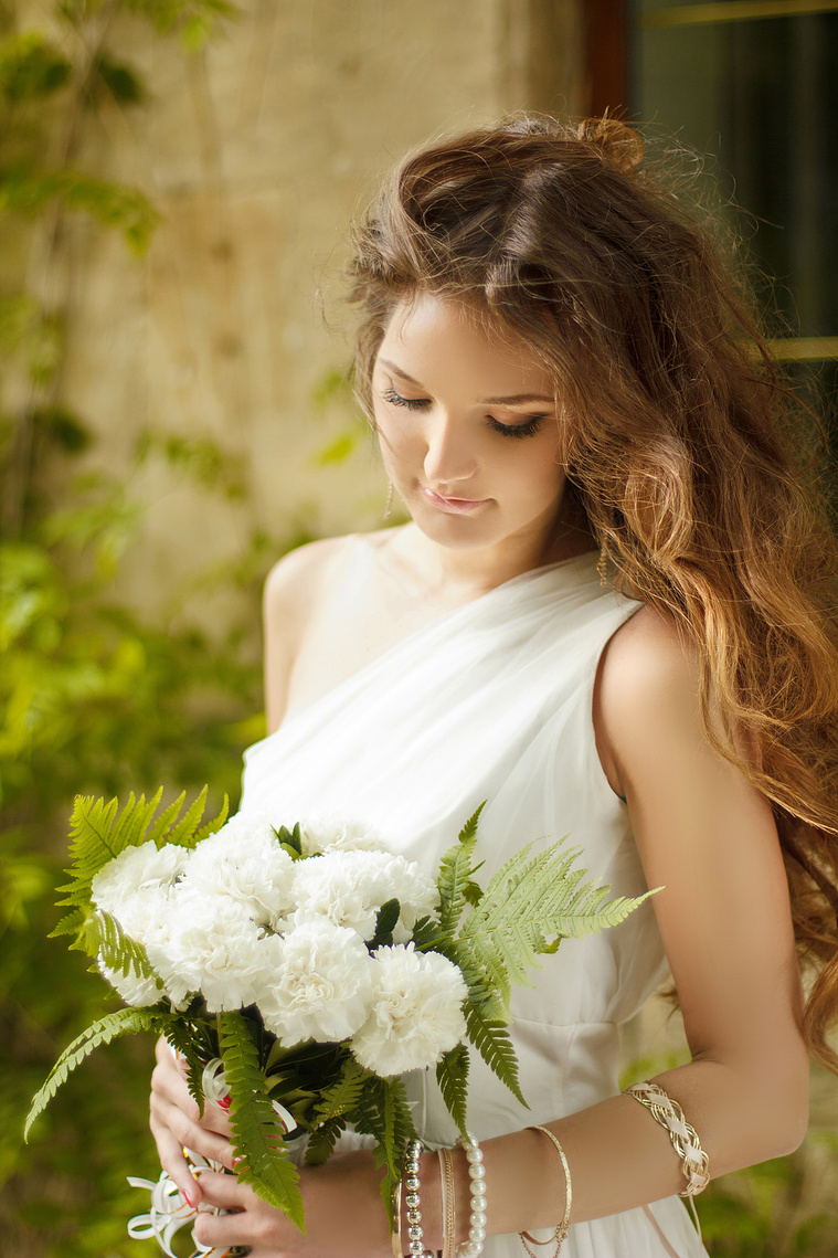 Bride is looking at her bridal bouquet at Captain James cottage in Melbourne. The flowers are from Hailey Page Flowers. The brides dress is Tania Olsen.  