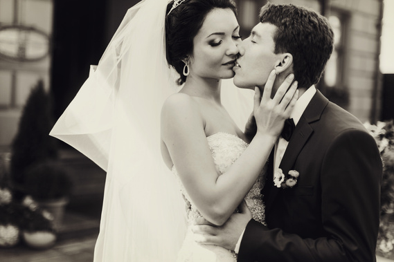 A romantic kiss of the groom with the bride. The bride is wearing a Alure dress. The groom is wearing a Versace suit.