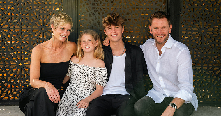 A family of four all dressed in monochrome sit on a bench.