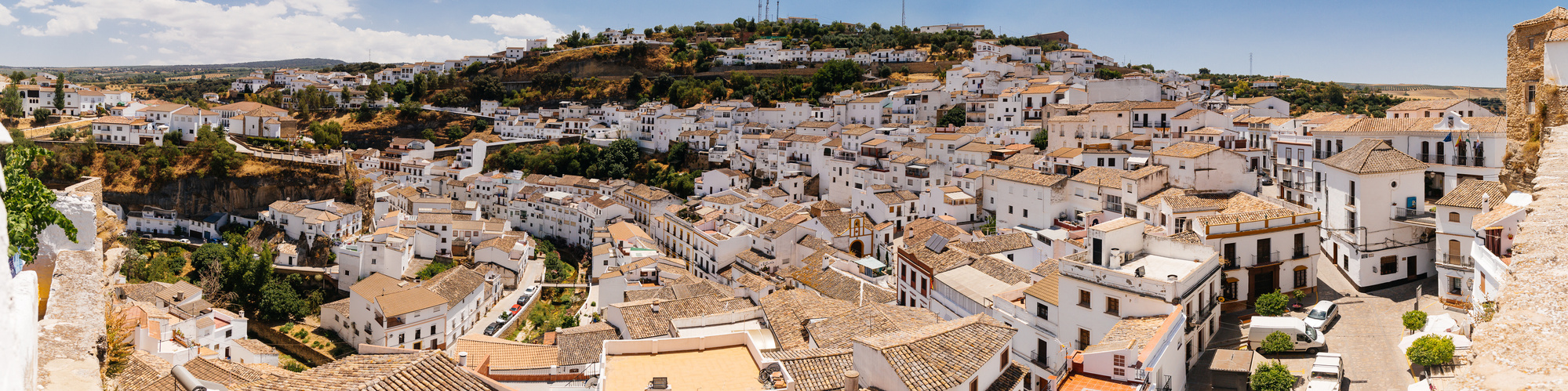 Panoramic view of the whitewashed buildings and green hillside of Setenil de las Bodegas, Spain 