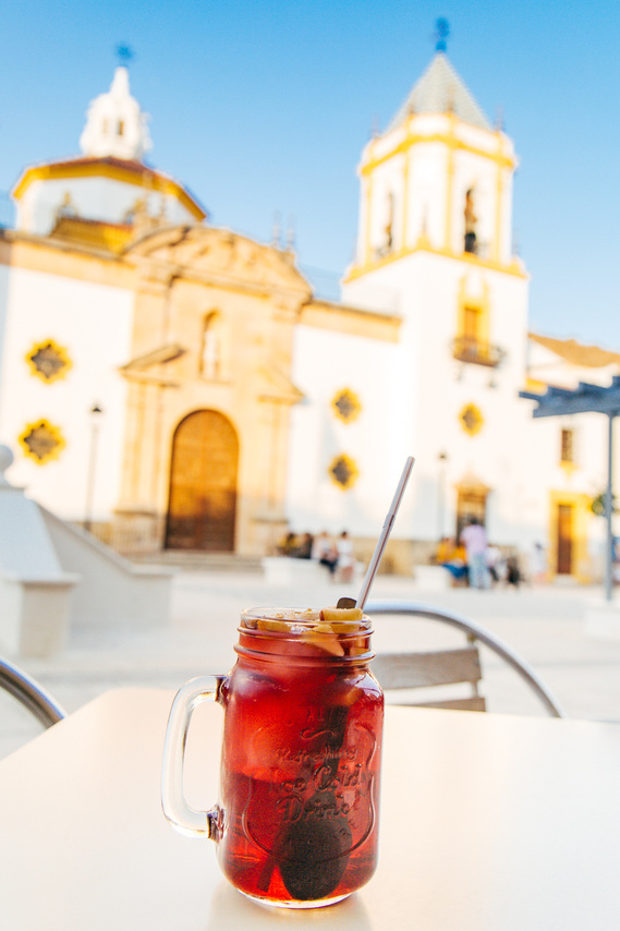 Mason jar of red sangria with the Nuestra Señora del Socorro church behind it in Ronda, Spain