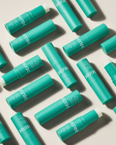 A dynamic flat lay featuring multiple Deinde skincare tubes, arranged for visual impact with clean, directional lighting. Photographed by Los Angeles product photographer Alex Kapustin at Rig Studio LA.