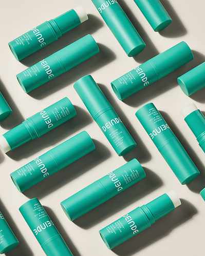 A dynamic flat lay featuring multiple Deinde skincare tubes, arranged for visual impact with clean, directional lighting. Photographed by Los Angeles product photographer Alex Kapustin at Rig Studio LA.