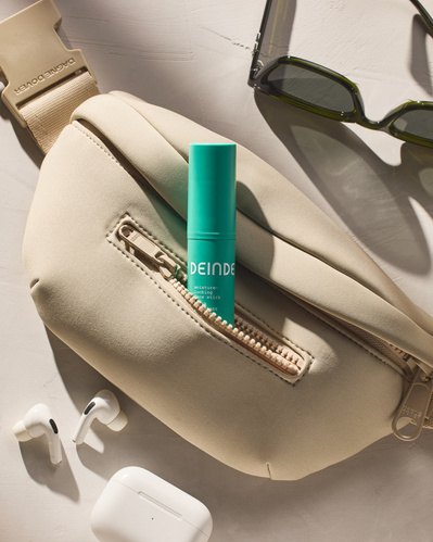 A stylish composition featuring Deinde skincare seamlessly integrated into an everyday fanny pack, highlighting travel-friendly beauty. Photographed by Los Angeles product photographer Alex Kapustin at Rig Studio LA.