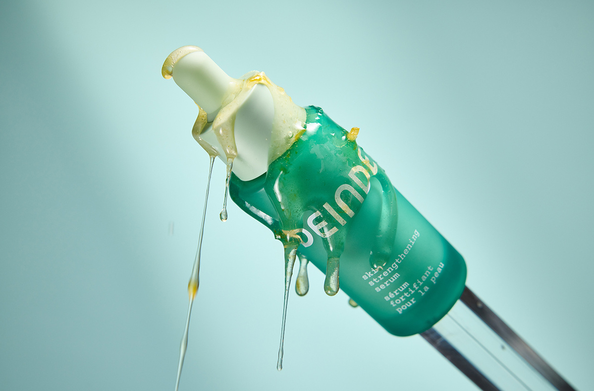 A striking product shot highlighting Deinde’s skincare serum infused with grapefruit extract, captured mid-air to emphasize its rich botanical formulation. Photographed by Los Angeles product photographer Alex Kapustin at Rig Studio LA.