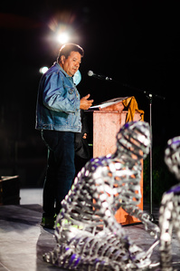 L'artiste Karl Chevrier se tient debout sur scène pour présenter son oeuvre, une sculpture en aluminium représentant deux figure agenouillées l'une devant l'autre, lors du rassemblement Miaja à Pikogan.