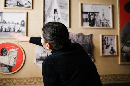 Une jeune femme observe des photographies en noir et blanc sur une installation d'exposition