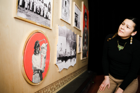 Une jeune femme observe des photographies en noir et blanc sur une installation d'exposition