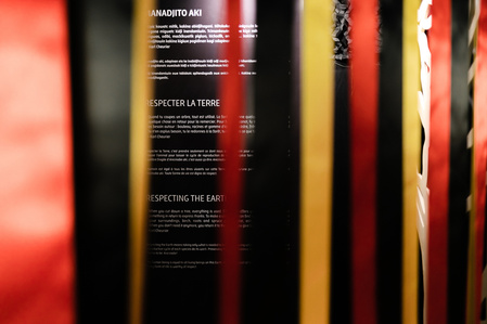 Un rideau de ruban rouges, jaunes et noir devant un texte d'exposition
