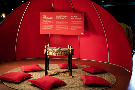 Un tambour traditionnel placé au centre d'un cercle de coussin sous un dôme de toile rouge