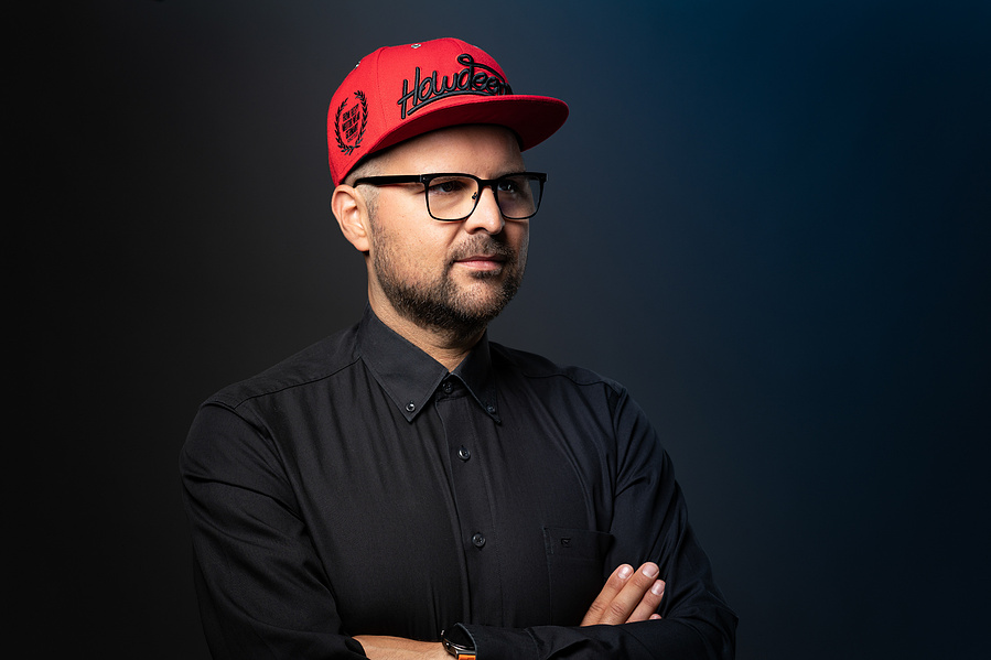 Ein unkonventionelles Businessportrait, das Individualität und Stil vereint. Die rote Kappe setzt einen bewussten Kontrast zum dunklen Hintergrund und vermittelt einen modernen Look. Perfekt für Kreativschaffende, Startups oder Personal Branding.