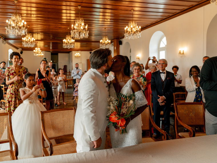 Des mariés dans la mairie décorée de lustres de Saint-Pierre à La Réunion avec un bouquet de fleurs tropicales. 