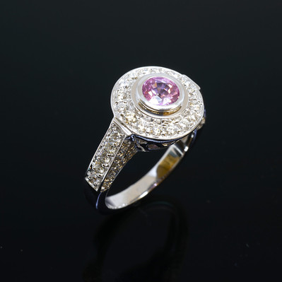 Enhance your elegance with a White Gold Ring featuring a stunning Pink Sapphire center, surrounded by a dazzling diamond halo. A perfect blend of color and sparkle for a timeless look.