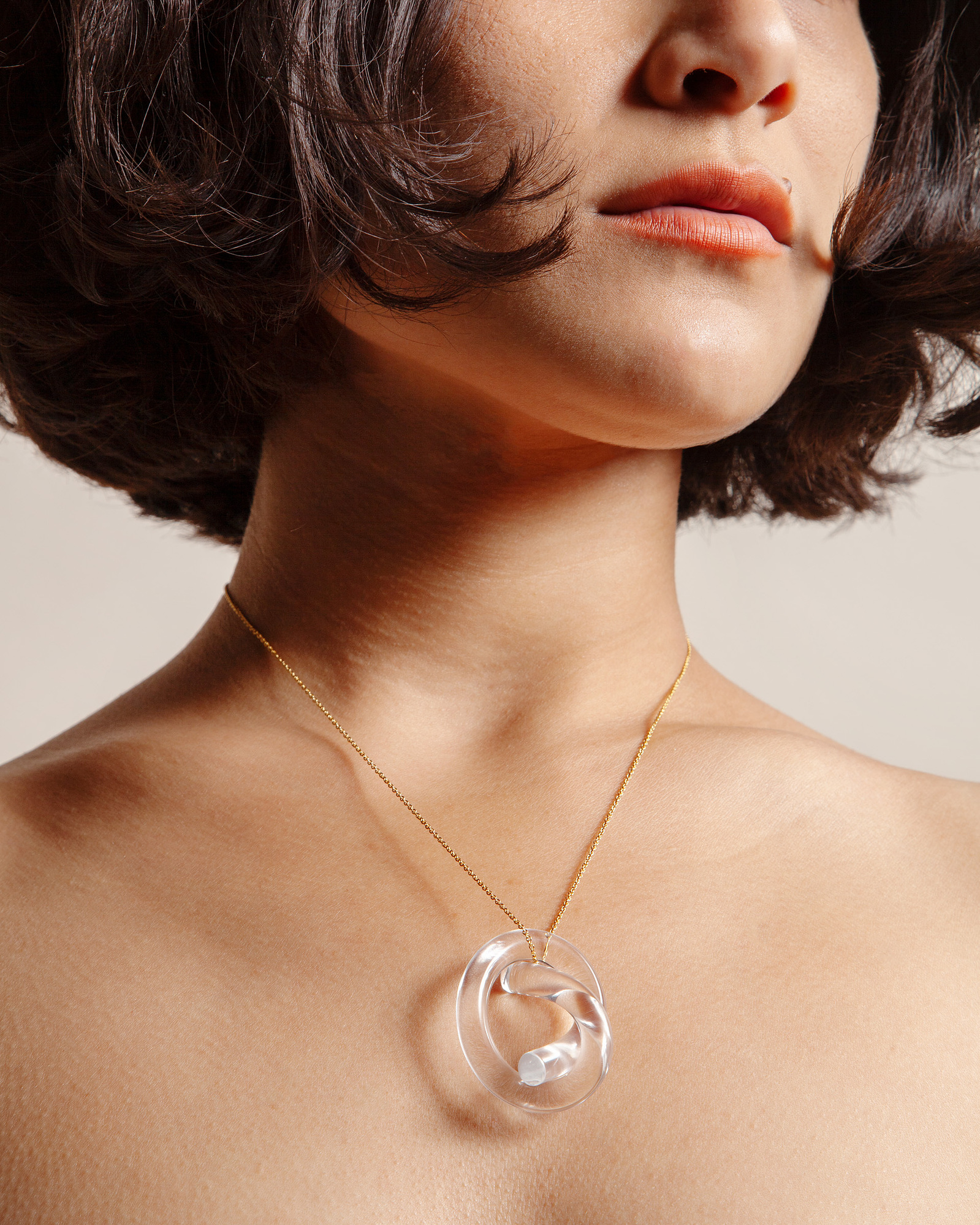 Female model photography of a woman wearing a Corey Moranis pendant necklace on a neutral background close up of jewelry
