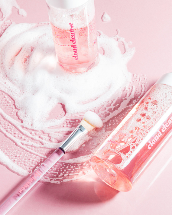 JB Lashes Pro Cloud Cleanse Foaming Wash on pink background flat lay with foam and bubbles and cleansing brush product photography prop styling by photographer stylist Becca M los angeles