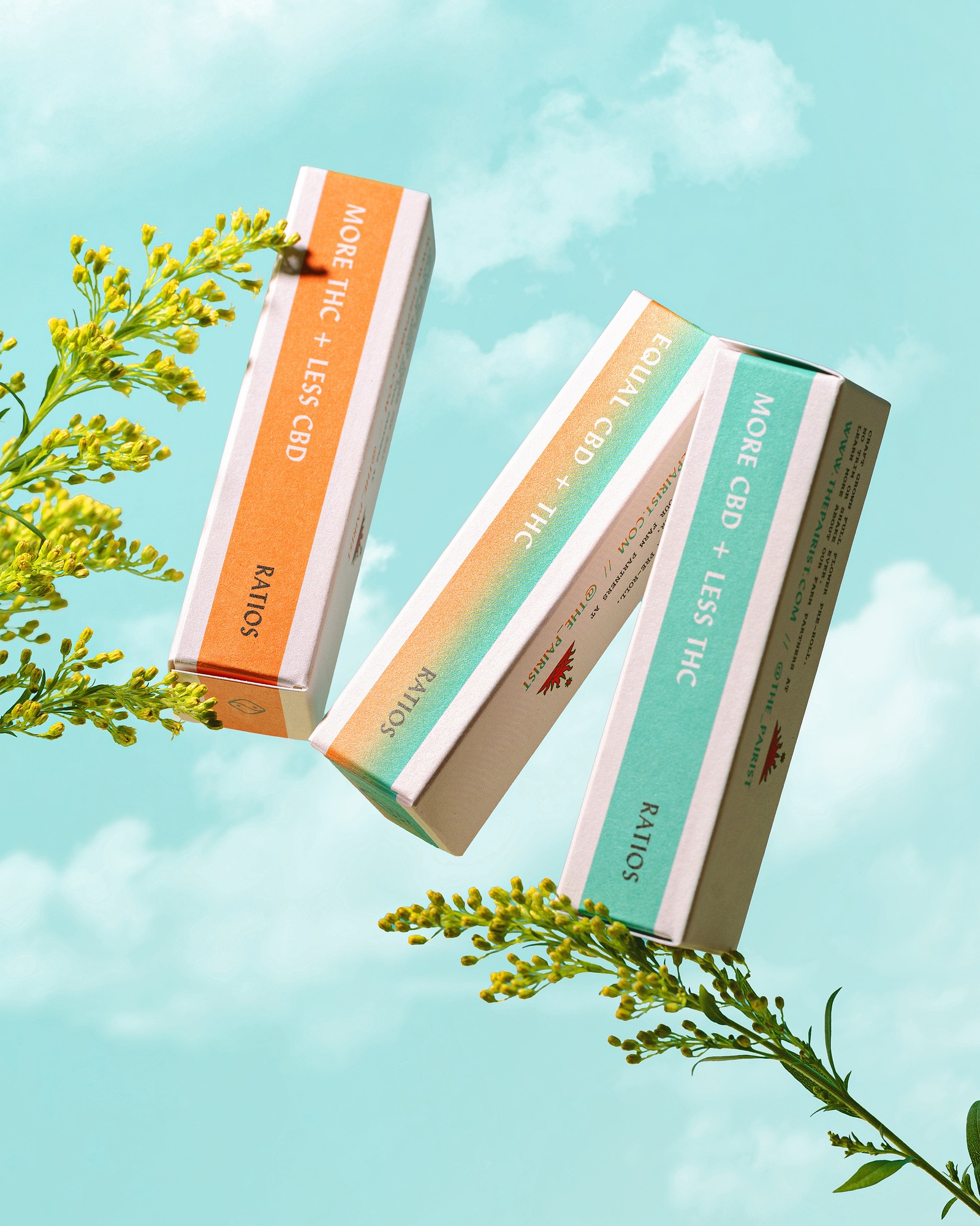 Three boxes of packaging joints with cannabis THC and CBD floating on green floral branches against a bright blue sky with clouds
