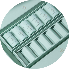 Product Packaging Photography and Styling by photographer stylist Becca M. Image of deodorant containers in the box, perfectly aligned with the other pieces of the package to show the logo and design of the product. In monochrome aqua seafoam color.