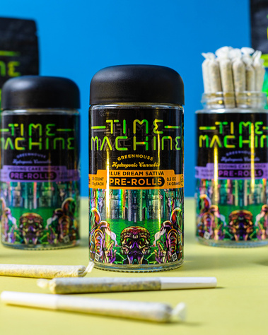 Time Machine Cannabis Brand Photography Close up of pre rolls with joints  laid out in the front and 3 jars lined up with a blue background and lime green surface