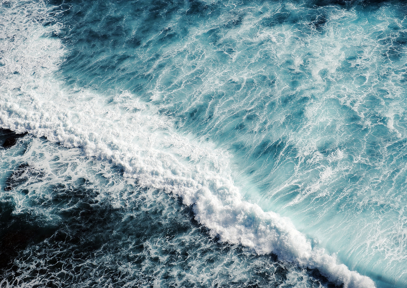 aerial image of a rough sea, crashing waves, foamy water