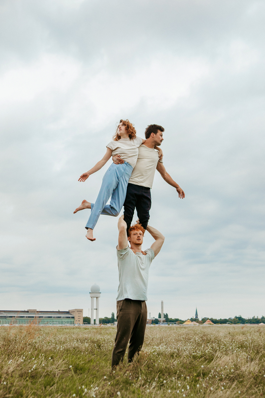 A human tower of three people. A man holds two people on his shoulders