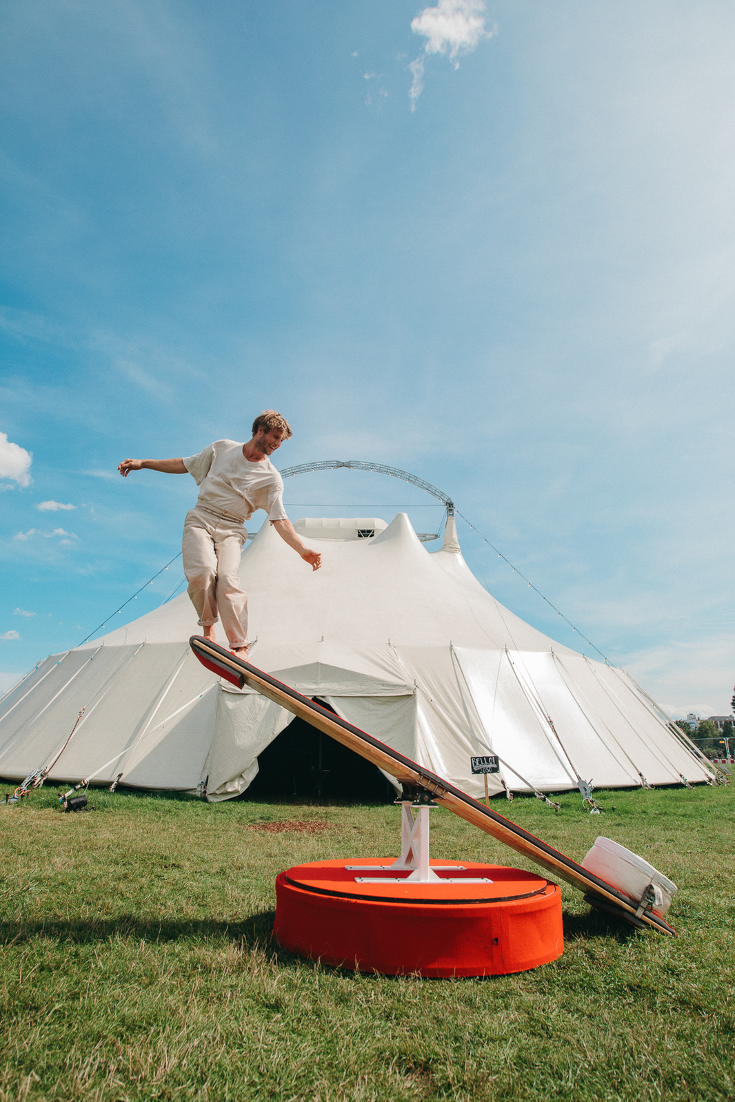 man dressed in white swinging in front of circus tent
