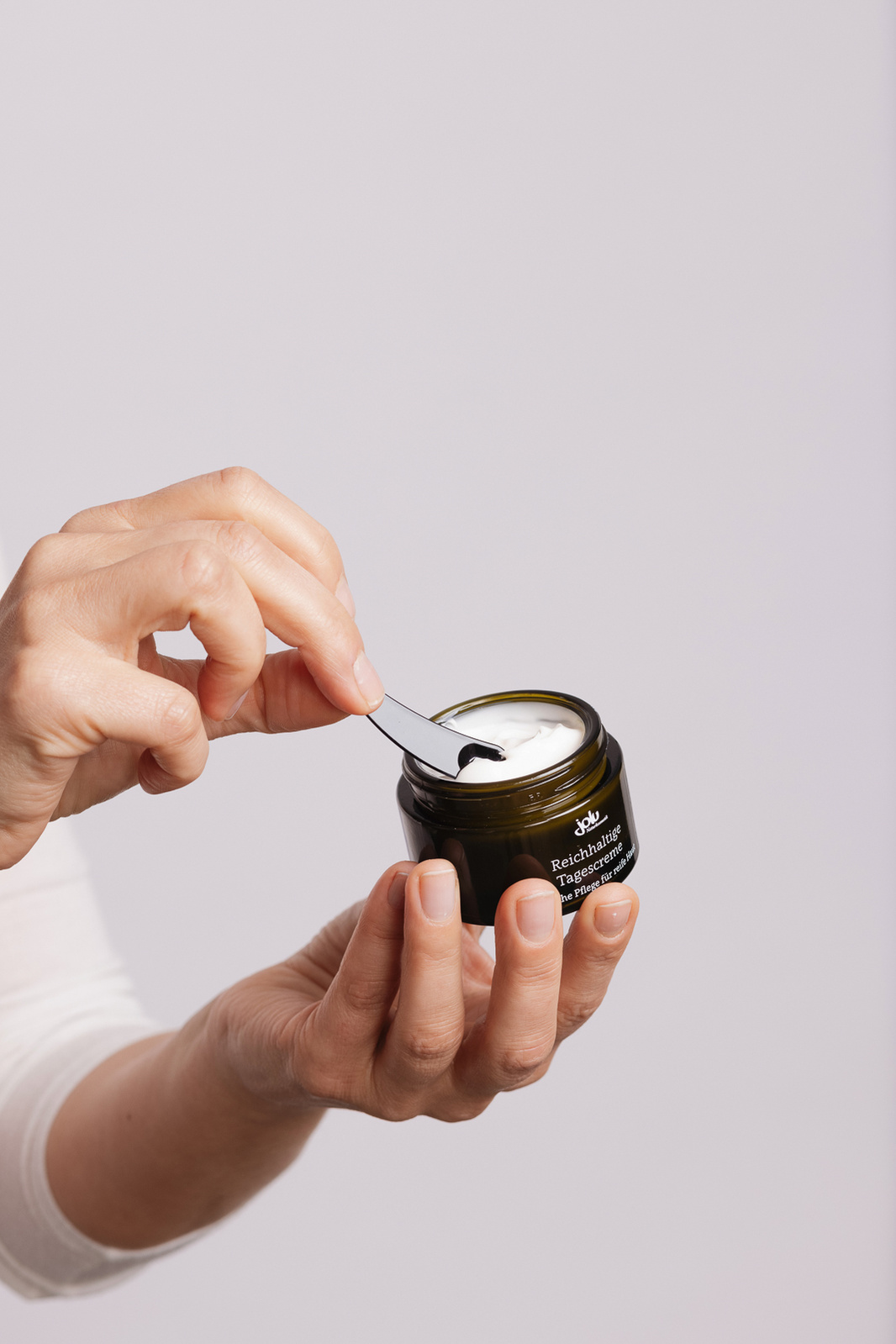 hand removing face cream with a cream stick 