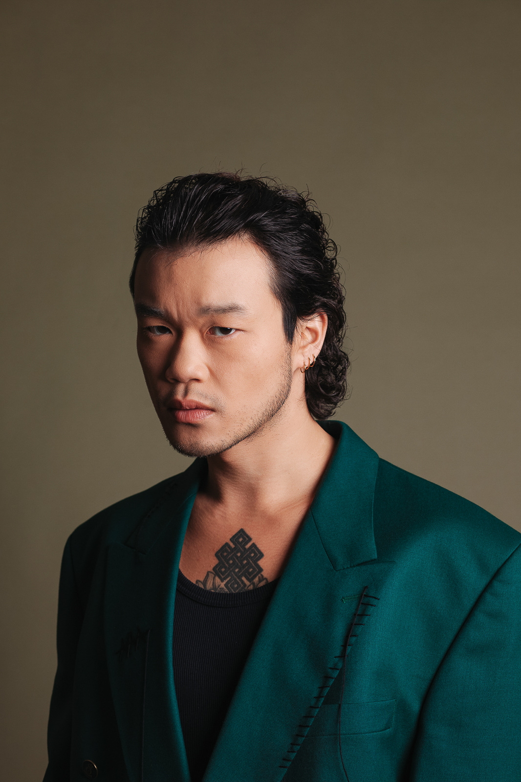 asian man looking at the camera with green clothes and green background