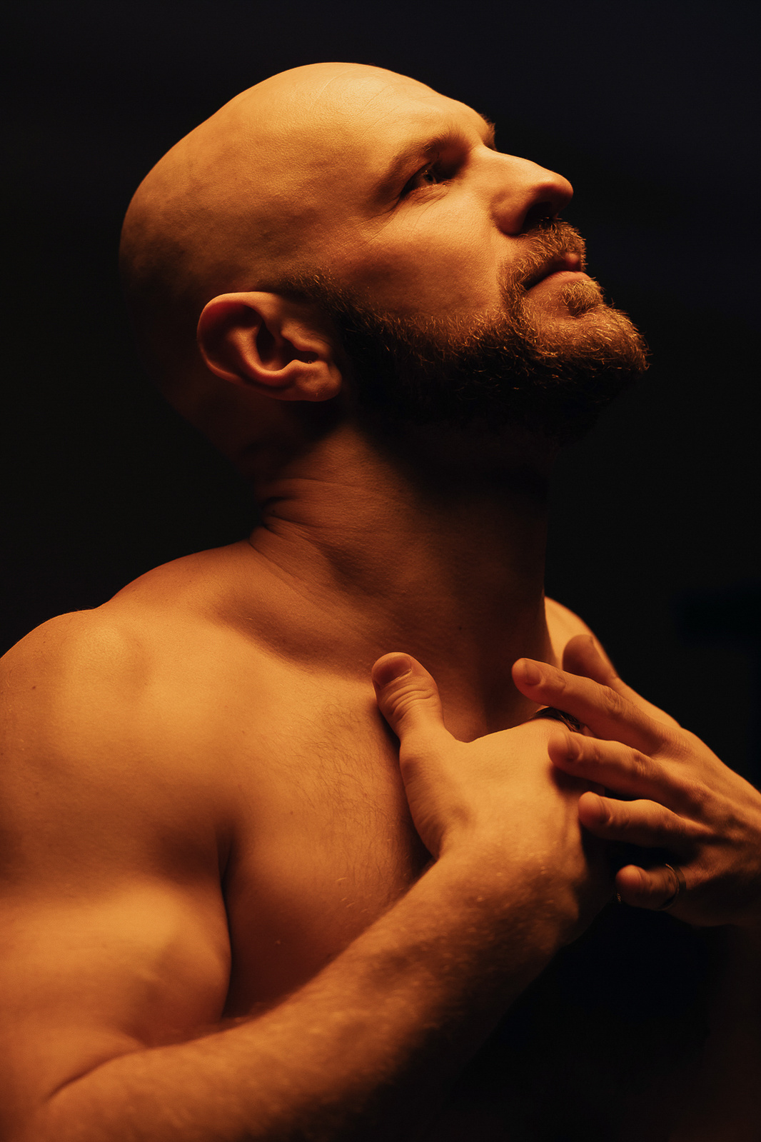 A shirtless man under an orange light