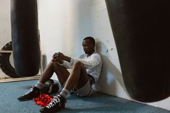 afro man sitting on the floor in a boxing gymnasium