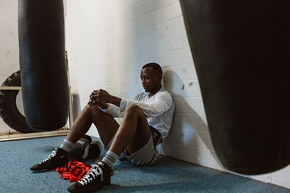 afro man sitting on the floor in a boxing gymnasium