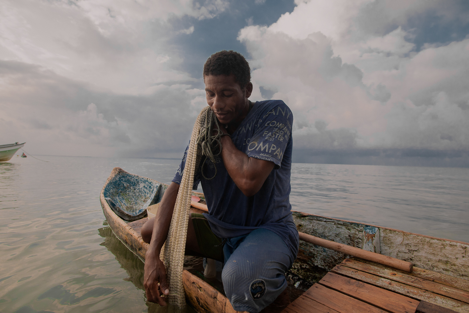 Fisherman in his boat fishing in front of a background of clouds and intense colors