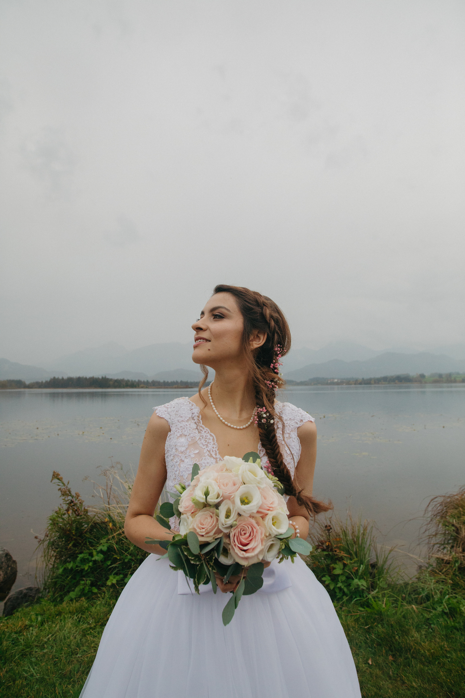 woman looking to her left with a bouquet of flowers in her hands and dressed in white 