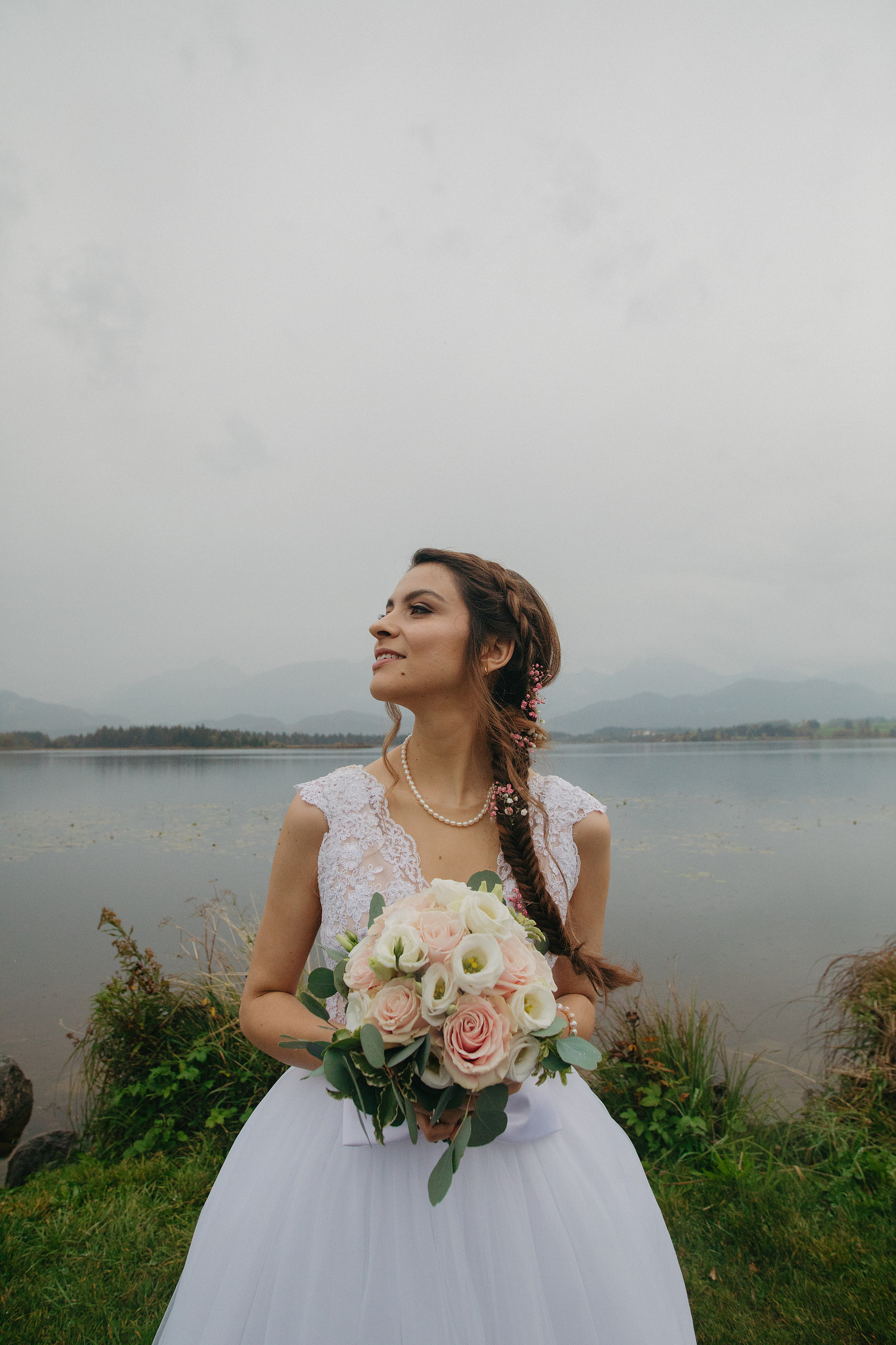 woman looking to her left with a bouquet of flowers in her hands and dressed in white 
