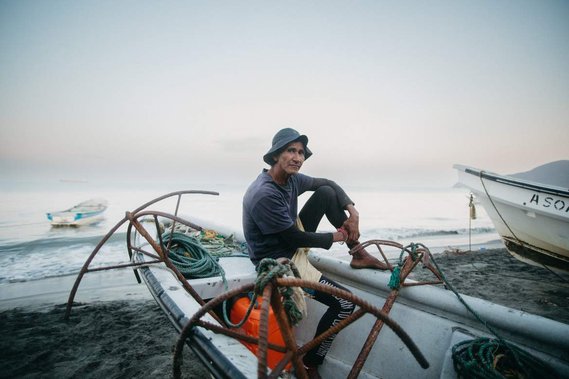 fish sitting on his boat at the front of the sea next to his anchor