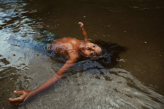 indigenous child floating on his back in river