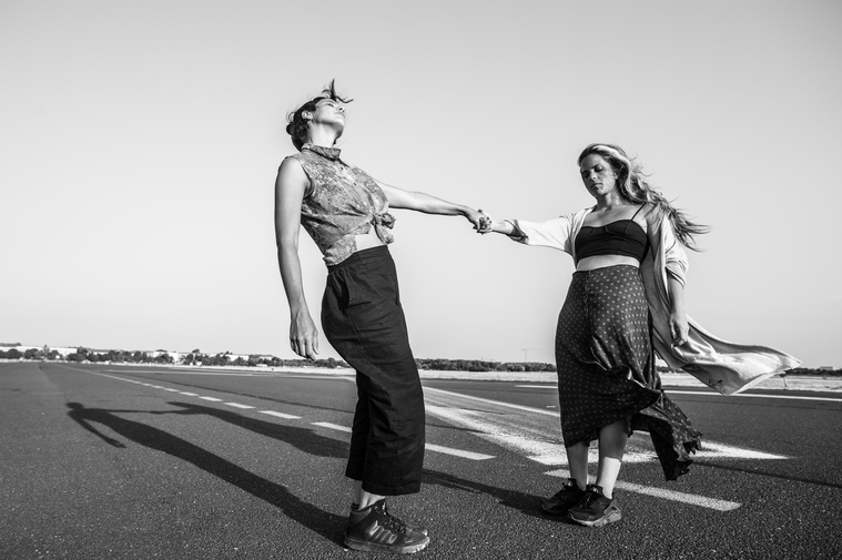 two women hold hands and dance in abandoned berlin airport
