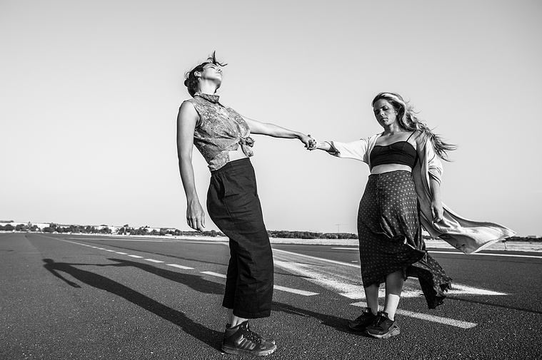 two women hold hands and dance in abandoned berlin airport