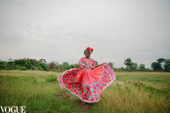 Afro woman dancing in her pink dress in open field