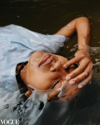 An indigenous girl lying in the river with water all around her