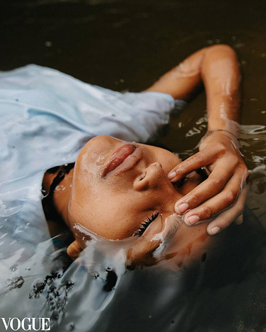 An indigenous girl lying in the river with water all around her
