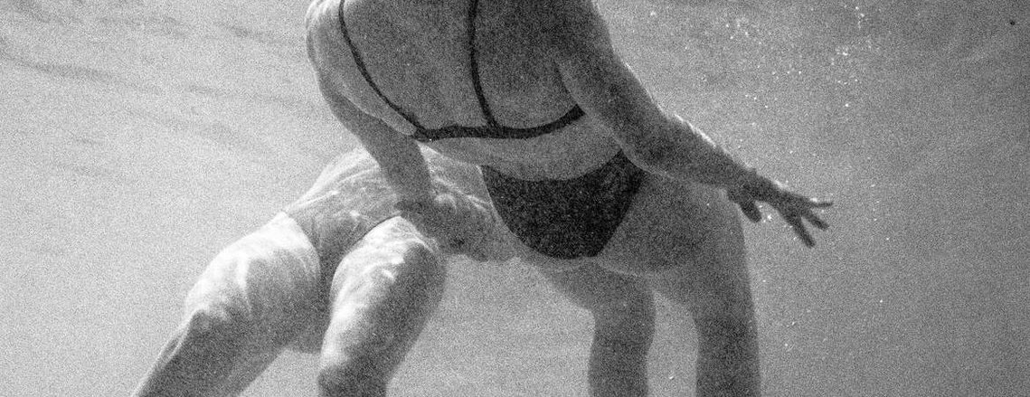 two women in bathing suits floating in a pool next to each other