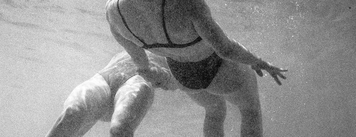 two women in bathing suits floating in a pool next to each other