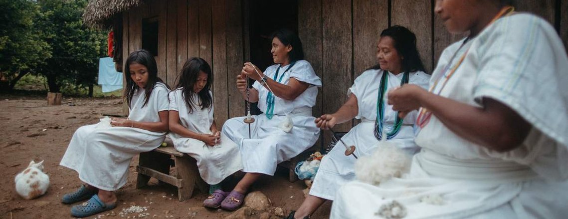 five seated women knitting with cotton