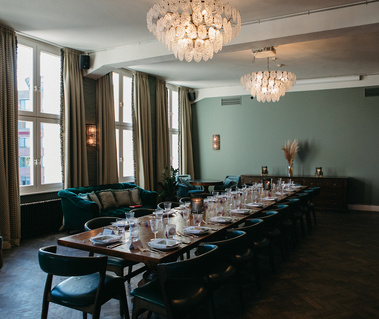 large living room with a long wooden table, plates, cutlery and crystal glasses.
