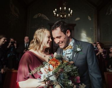 couple laughing and woman holding a bouquet of flowers with her partner